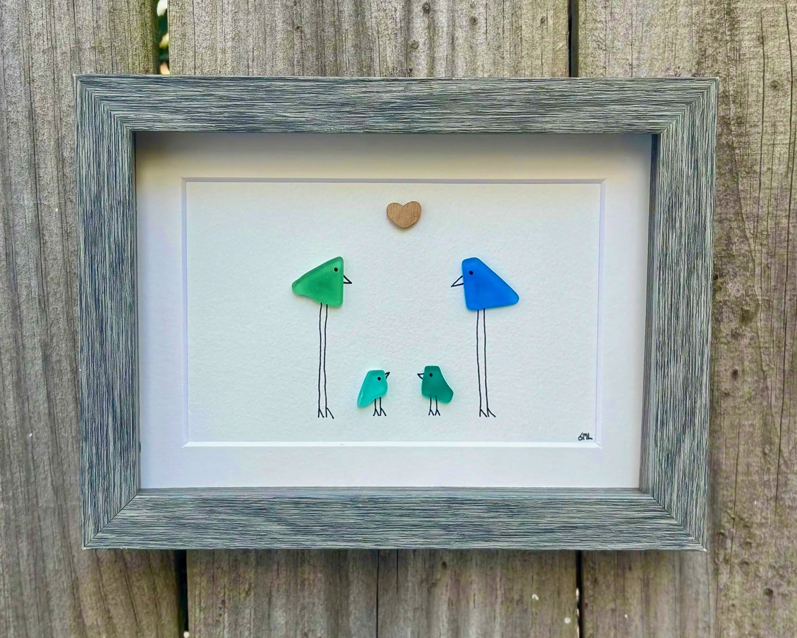 Framed artwork representing a family of 4 through colorful birds, in a faux wood, shadow box with glass front frame.