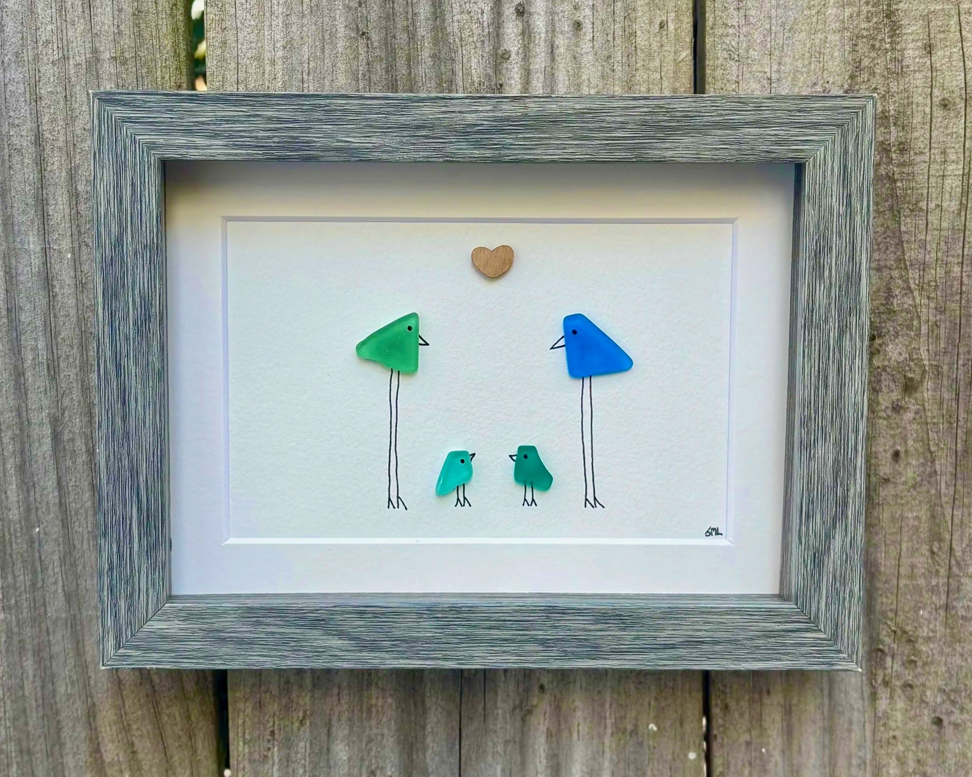 Framed artwork representing a family of 4 through colorful birds, in a faux wood, shadow box with glass front frame.