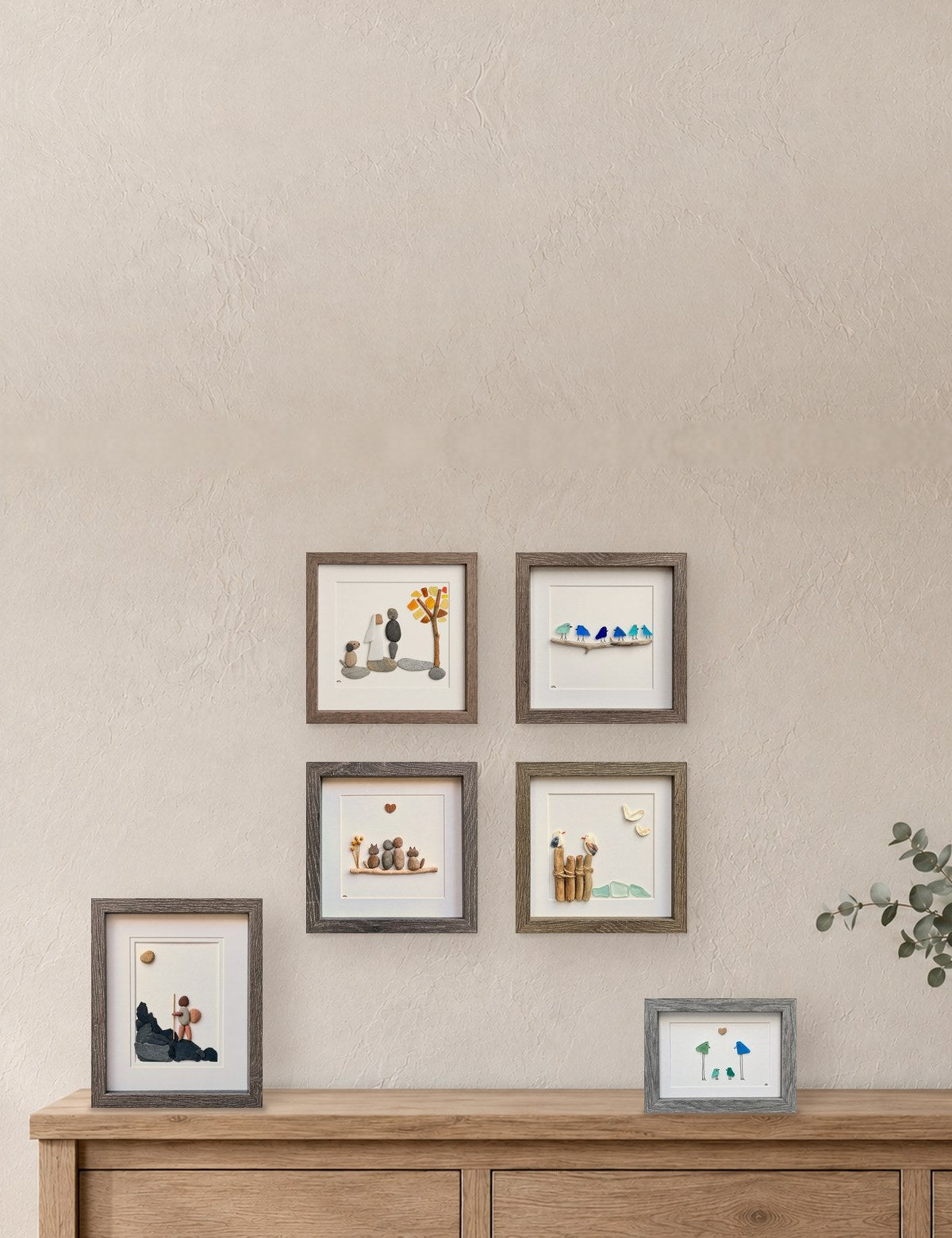 Sea glass and pebble art displayed on a wall and sideboard